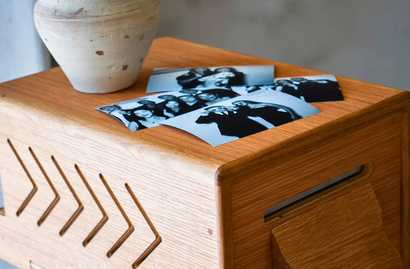 Photo booth postcards placed at the top of a wooden printer shell.
